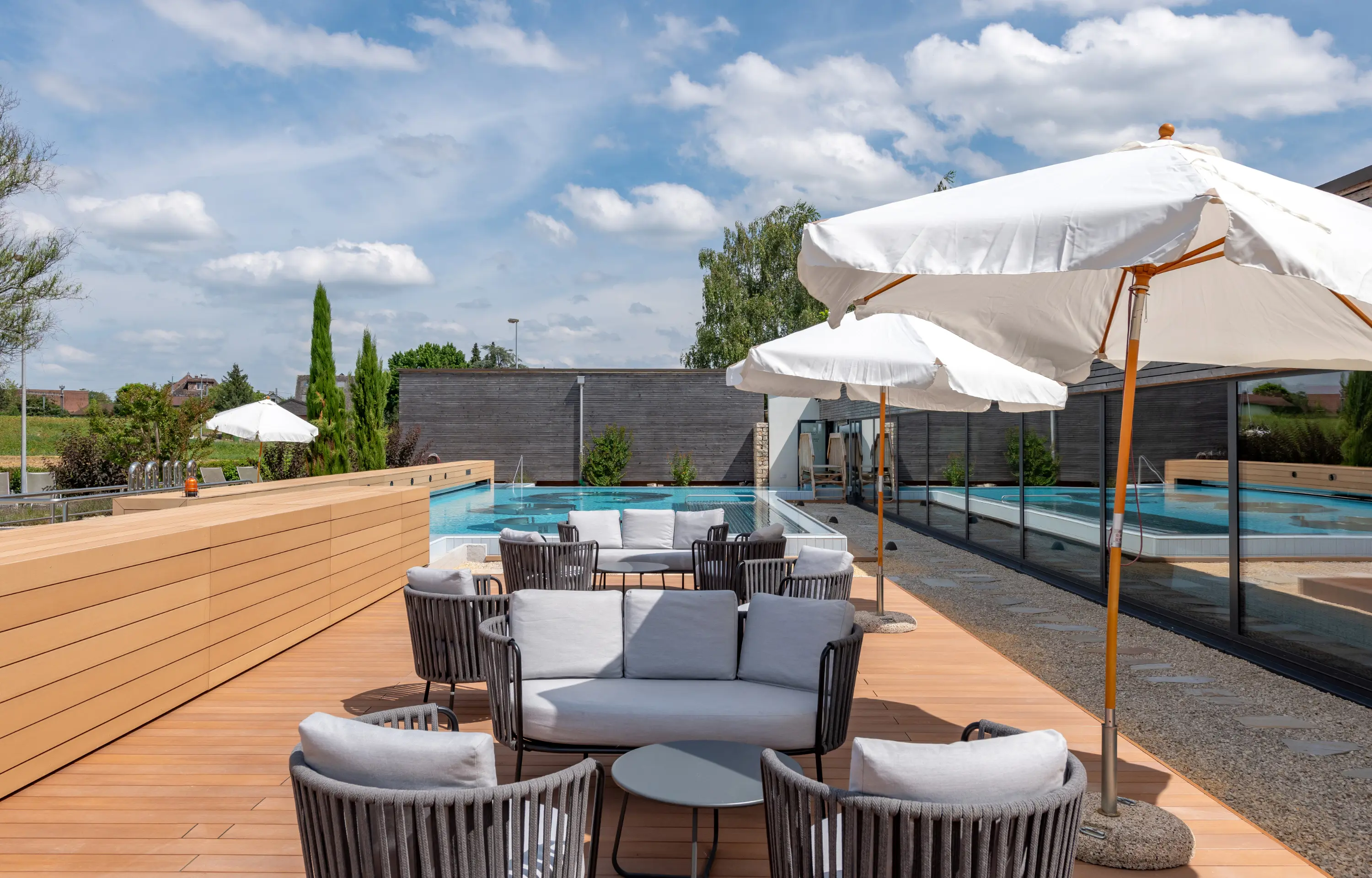 Lounge- und Ruhebereich im Aussenbereich und Blick auf das Aussenbecken.