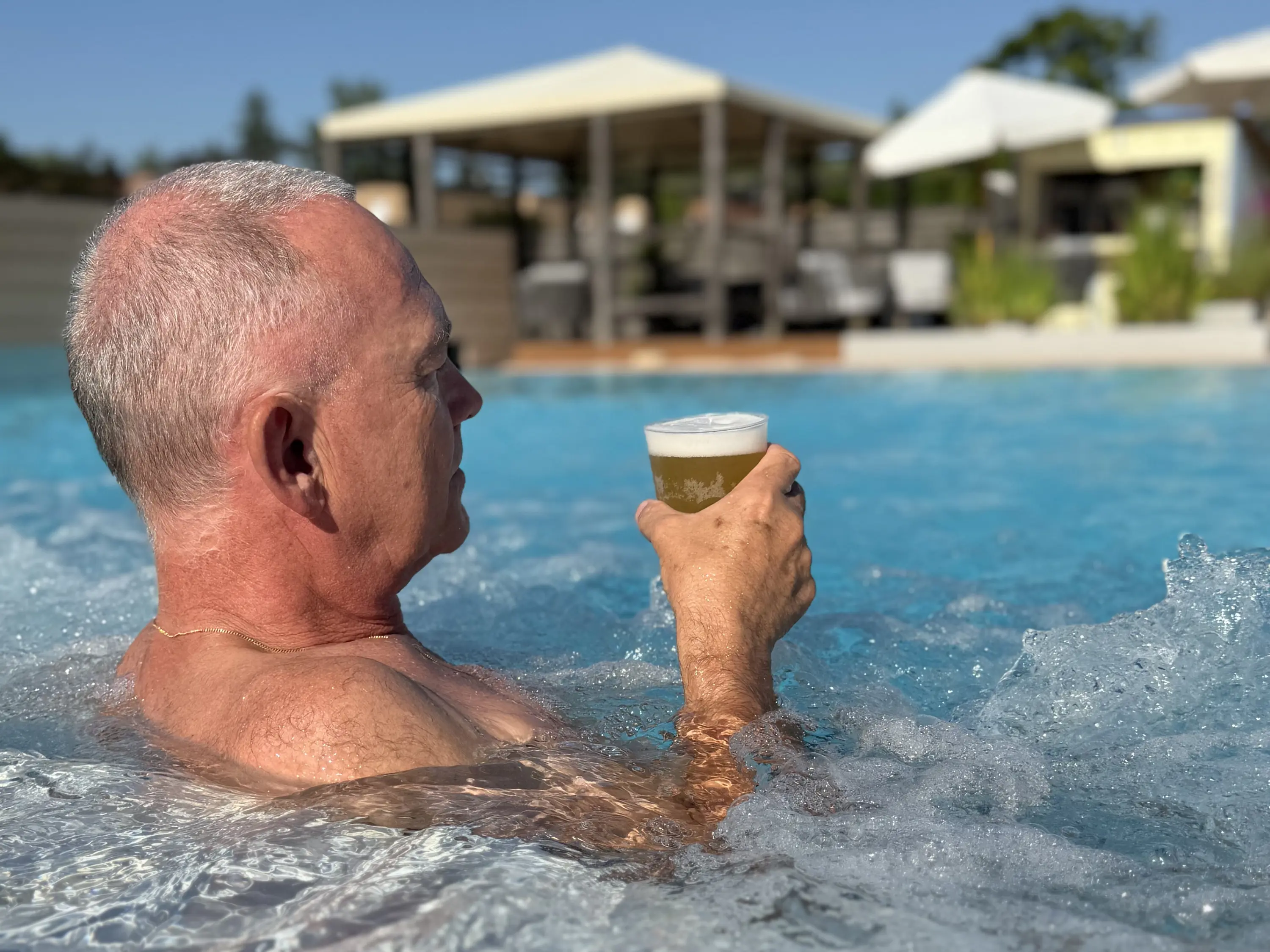 Gast entspannt im Aussenbecken mit einem erfrischenden Getränk.